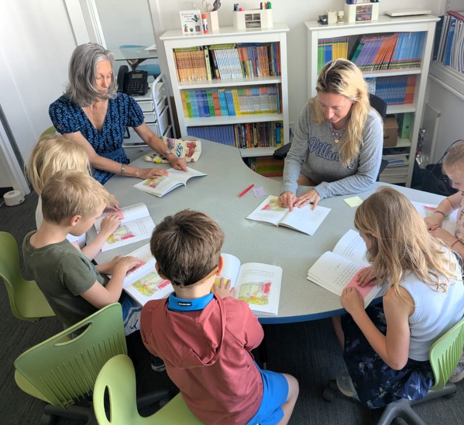 Elizabeth and a teacher leading a small-group reading lesson with young students